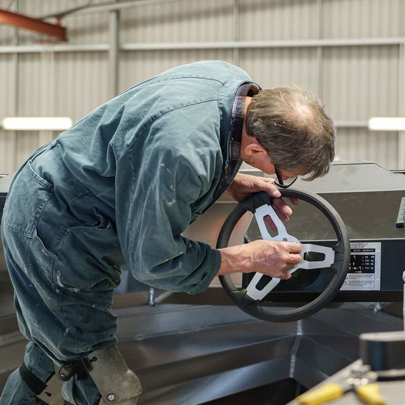 Workshop tradesperson fitting a marine helm on the floor